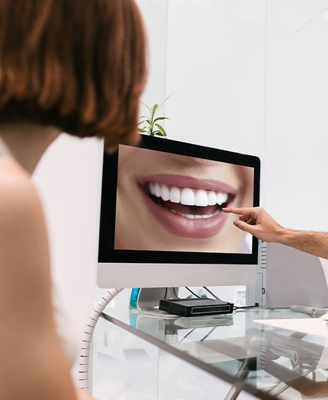 Dentist and dental patient reviewing smile makeover design on computer screen
