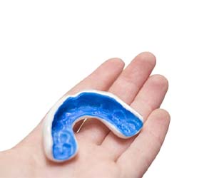 Hand holding a mouthguard to prevent dental emergencies in Fayetteville